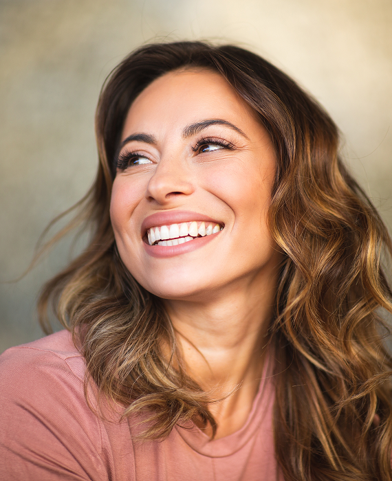 Smiling woman looking into mirror brushing her teeth smoothly